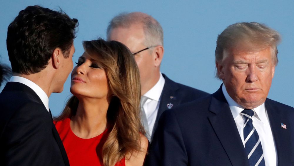 Justin Trudeau, Melania Trump and Donald Trump standing on an outdoor stage getting ready to address the public. Melania is looking at Justin like she could kiss him while Donald Trump, off to the side, looks dejected, abandoned and despicable. 