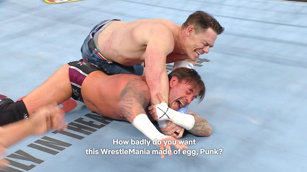 Screenshot of John Cena trying to pin CM Punk in WWE's limination Chamber event. Subtitle reads: "How badly do you want this Wrestlemania made of egg, Punk?"