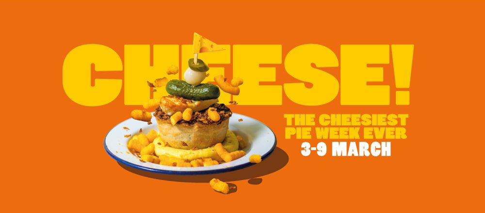 Advertising image of a limited edition cheese-themed pie. It appears to be a bed of mashed potato, then a pie, then fried halloumi, then a pickle, then an onion, then a slice of jalapeno, all garnished with a handful of cheesy wotsits. 
