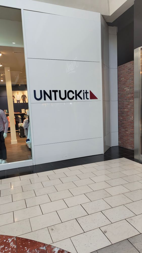 photo of a sign on the side of a building that reads "untuck it"