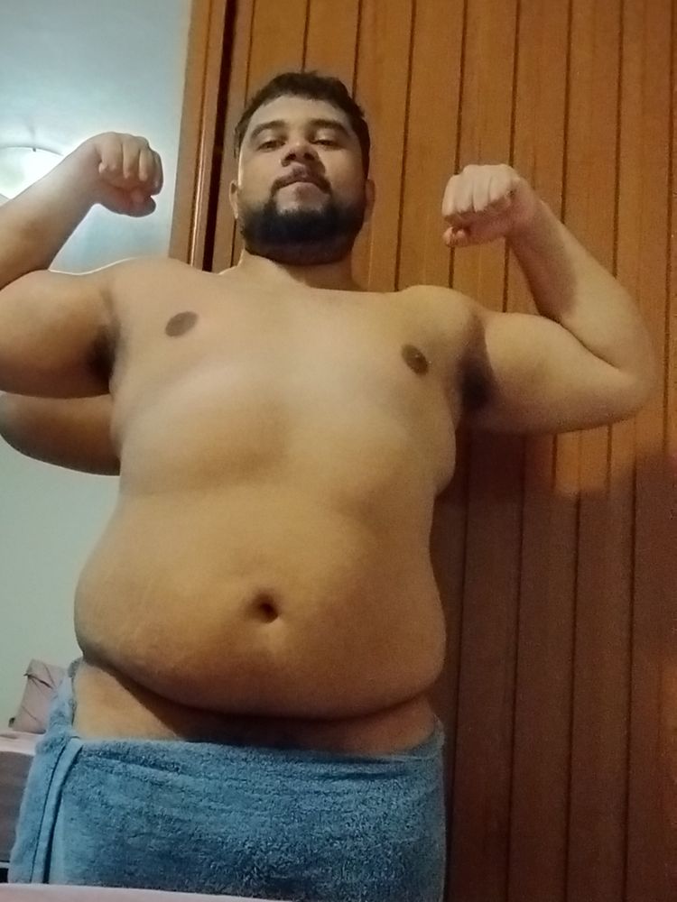 Eu só de toalha flexionando os bíceps enquanto faço "bear face"