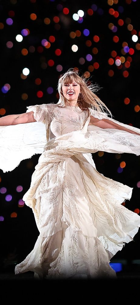 Taylor Swift at The Eras Tour during FolkMore set spinning in her white dress. The dress flies around her.