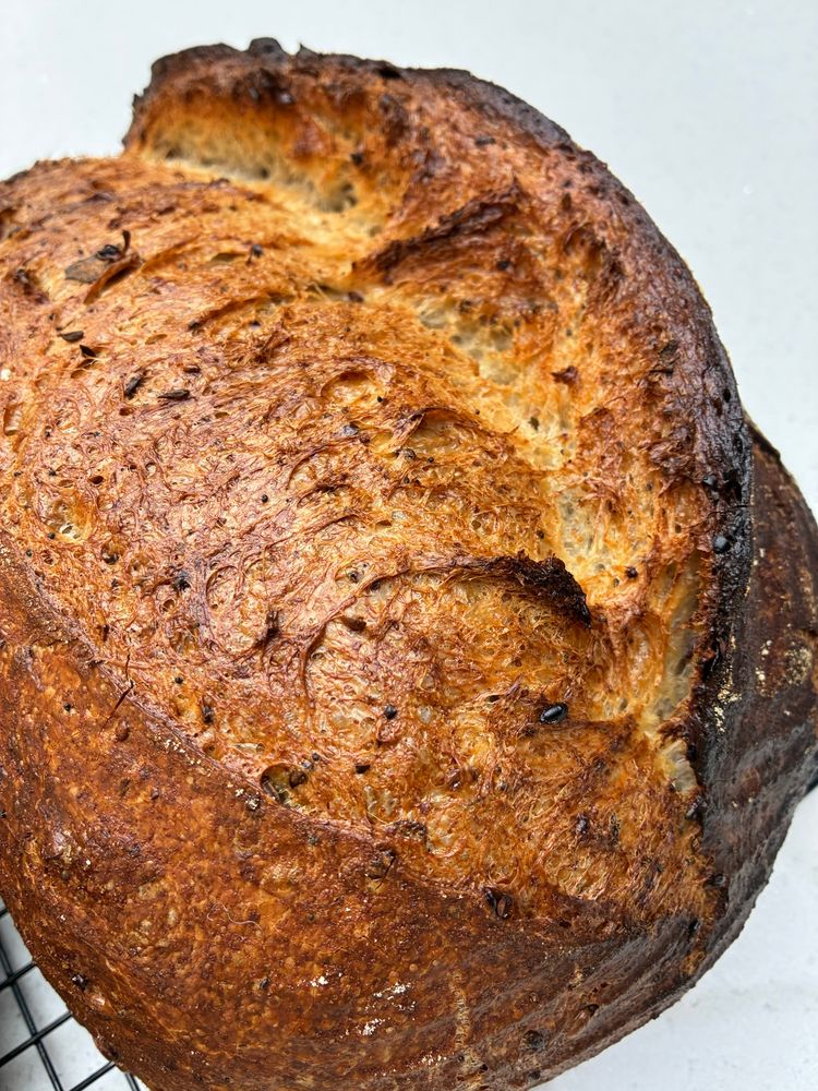 Golden seeded sourdough showing gluten strands, seeds and sage.