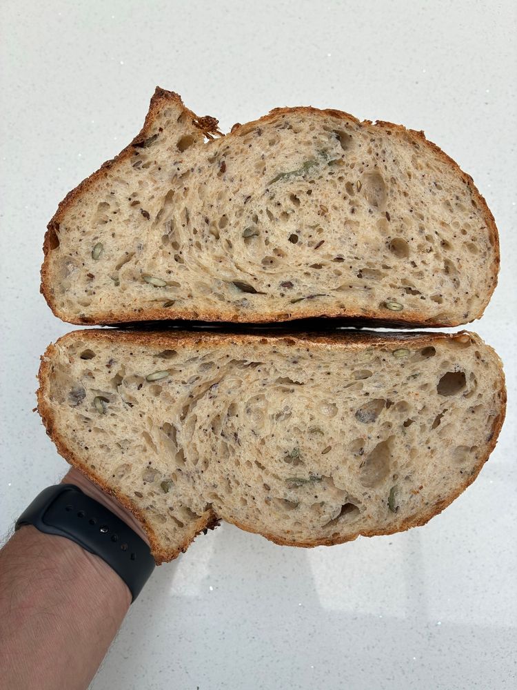 Sourdough crumb shot showing open texture, seeds and sage.