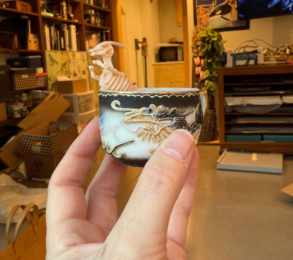 A skeletal diplodocus rides in a tiny Japanese demitasse cup. 

Why? 

WHY NOT. 