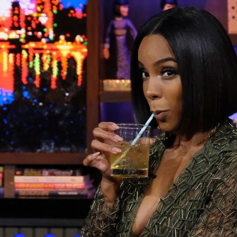 Picture of Kelly Rowland in a bob, sipping an alcoholic beverage through a straw while giving a side eye and looking to her left.