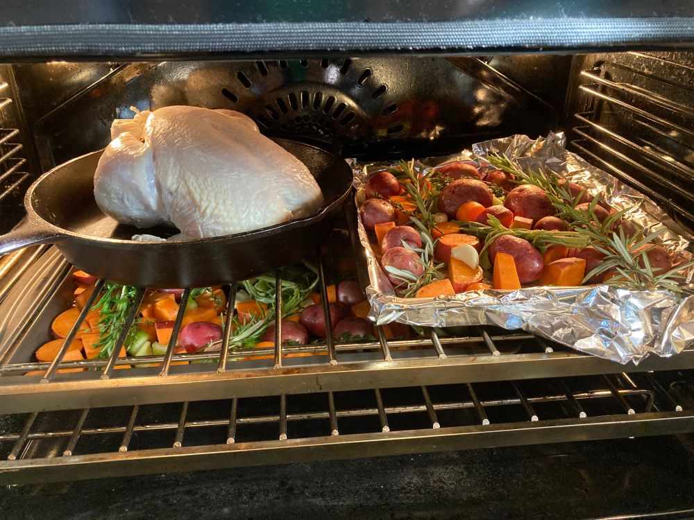 Chicken and veggies loaded into an oven ready to roast