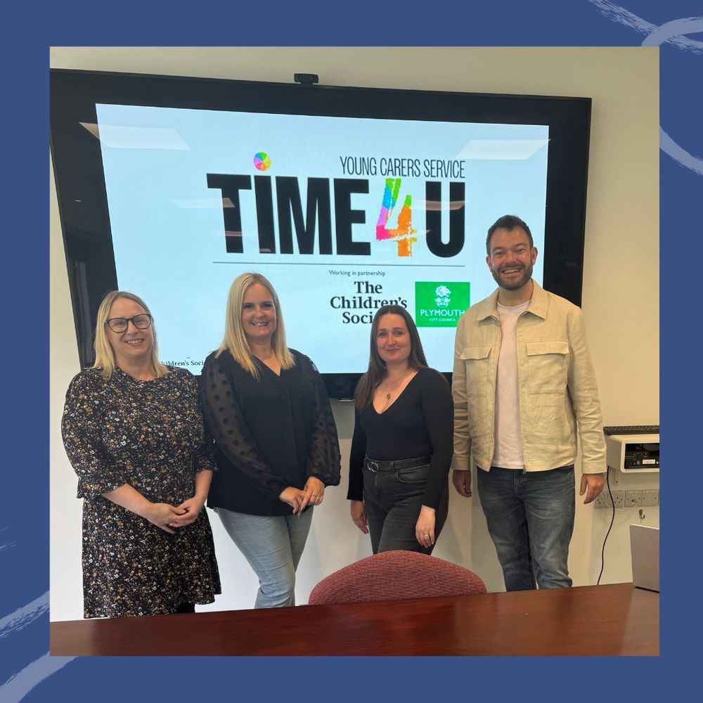 Four members of staff standing in front of a young carers service sign 'Time for You'.