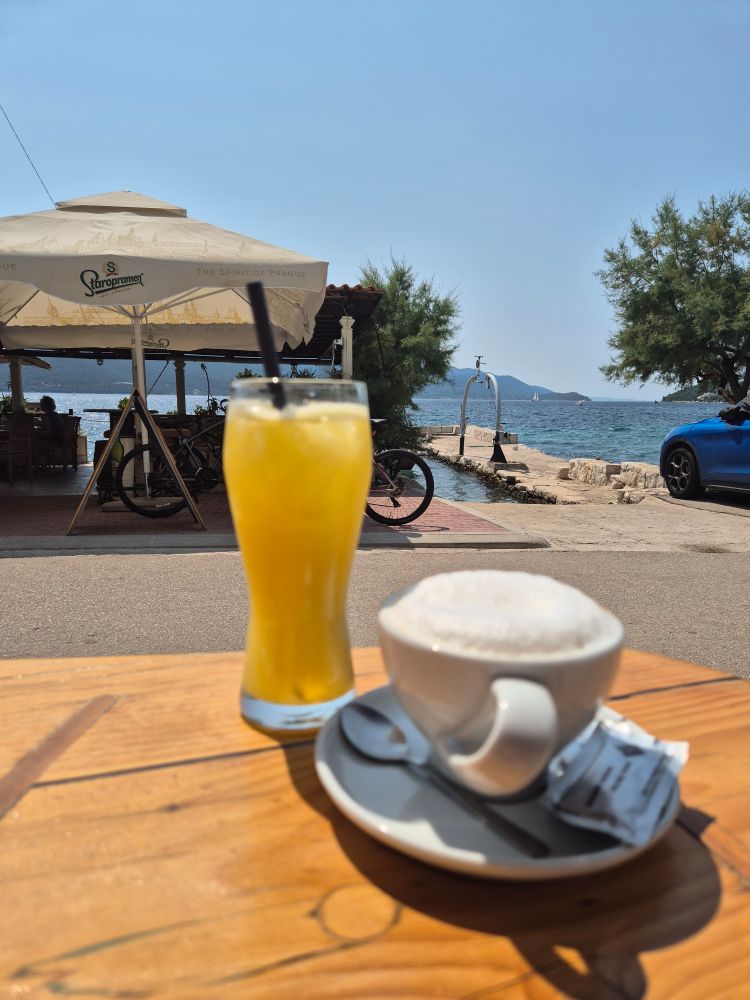 Cappuccino und Orangensaft vor Bar vor Adria. 