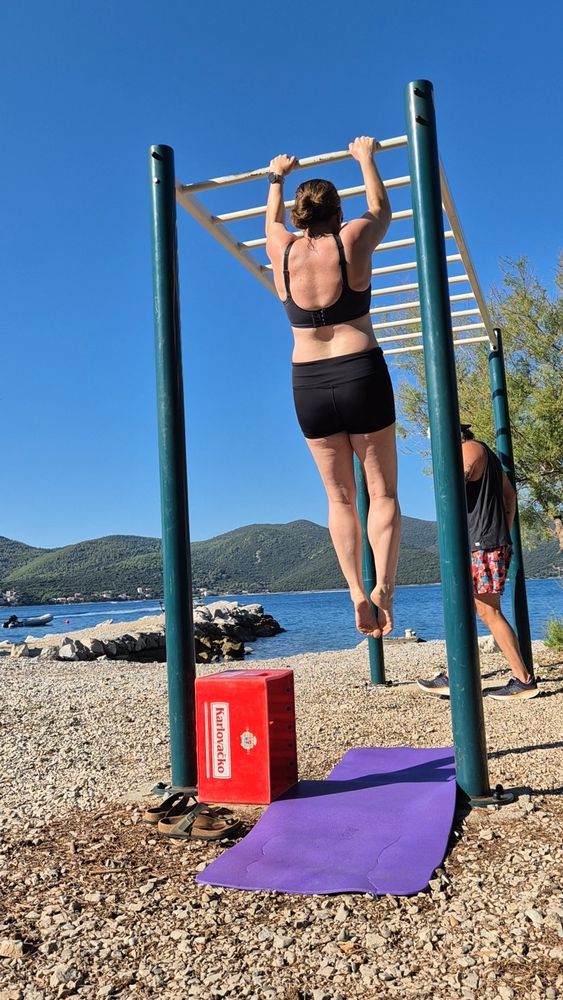 Nina macht Klimmzüge an einer Trainingstation in einer Bucht.