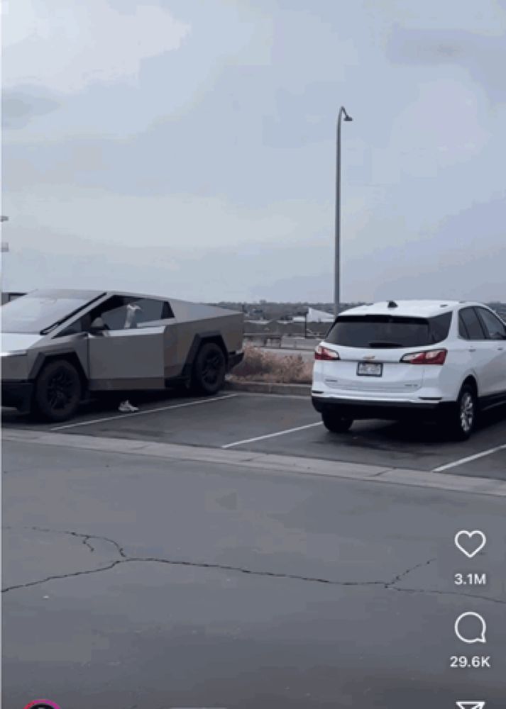 a white chevy equinox is parked next to a silver tesla