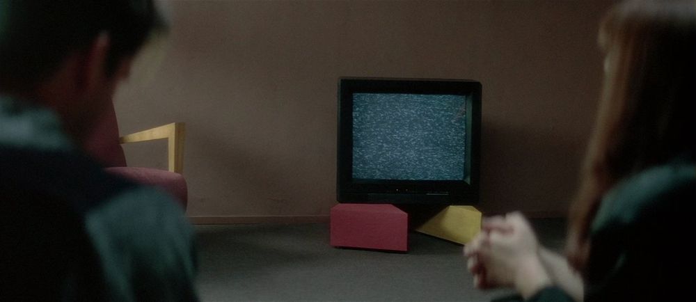 lost highway's dingy analog tv held up by a red and yellow triangles