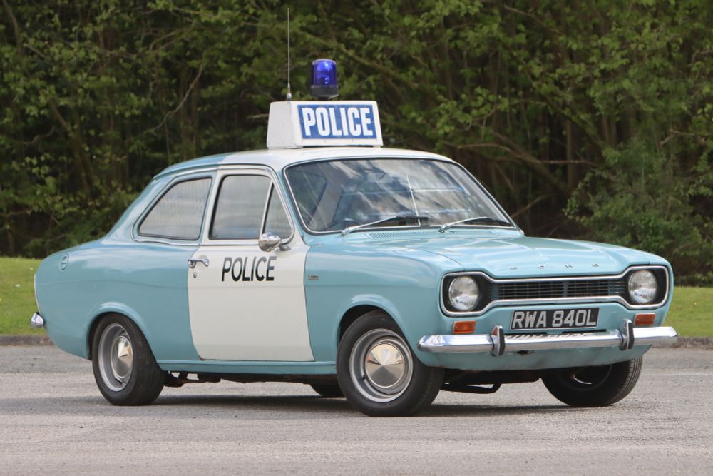 Blue and white Ford Escort mk1 with Police on the door and flashing mee-maw on the roof