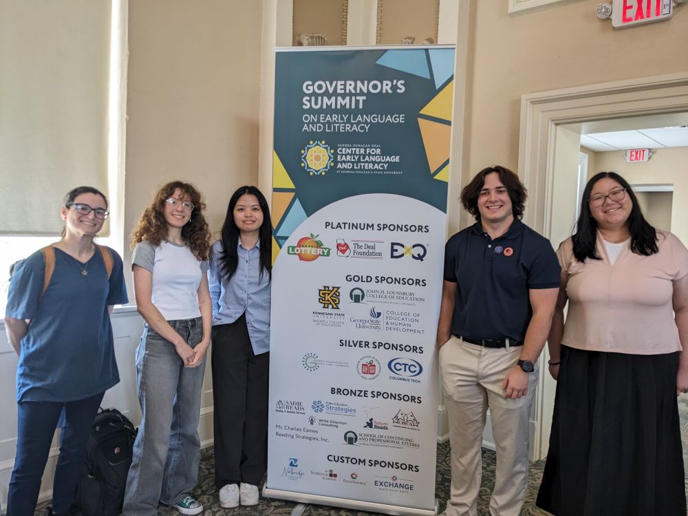 Our LSS team standing in front of the Governor's Summit sign.