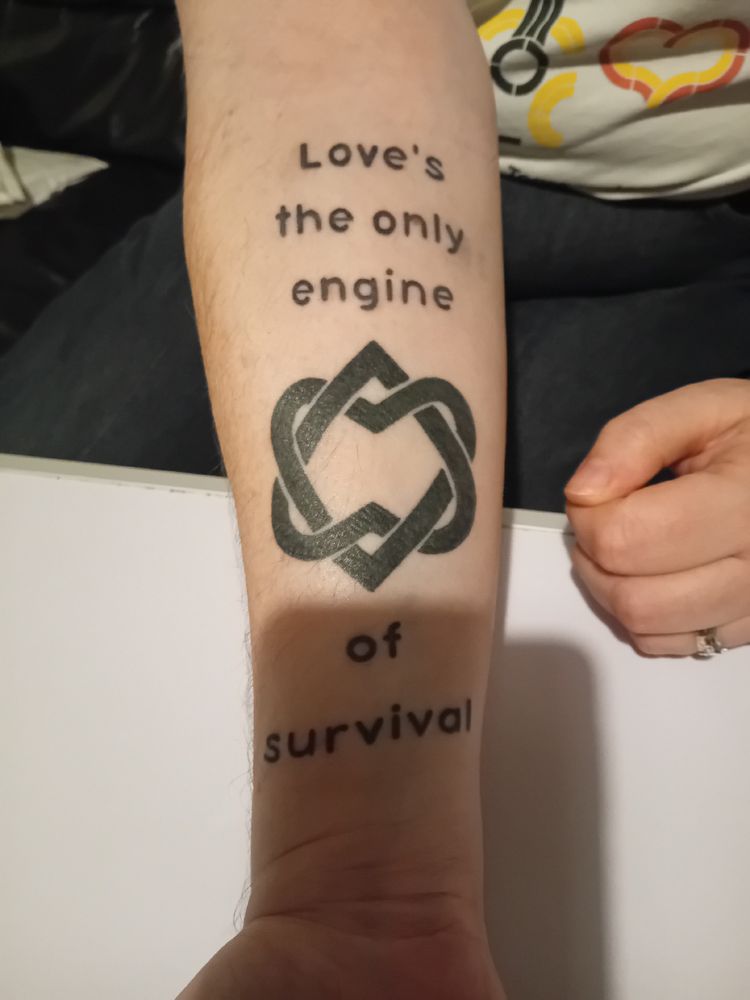 A line from Leonard Cohen's song The Future ("Love's the only engine of survival") tattooed on my arm along with his Unified Heart symbol. 