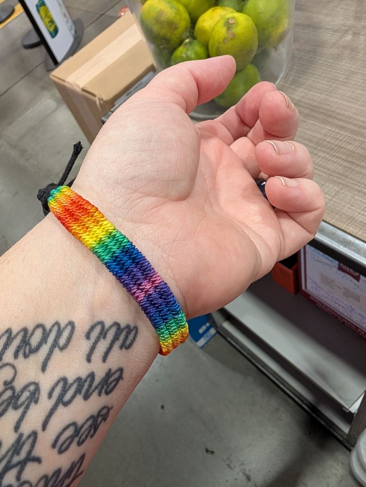 A hand with a rainbow woven bracelet 