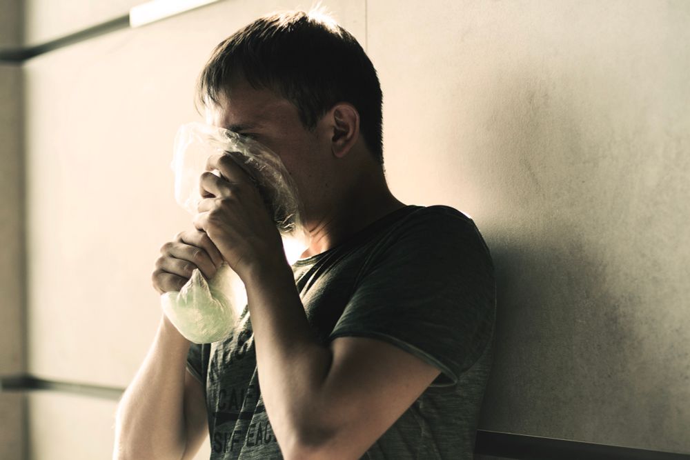 A man inhaling/huffing a drug