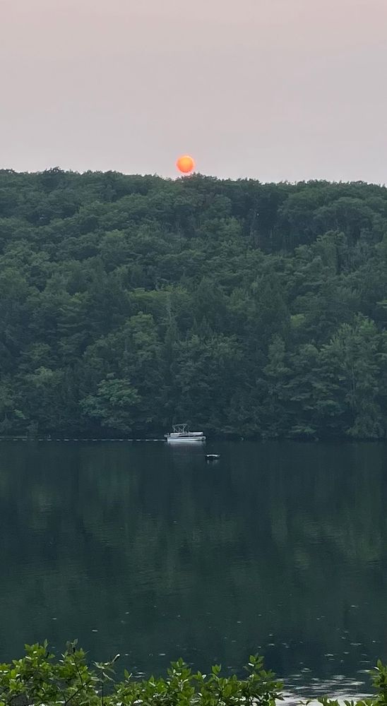Sunset over a pond. Sunlight being filtered by smoke from distant Canadian forest fires
