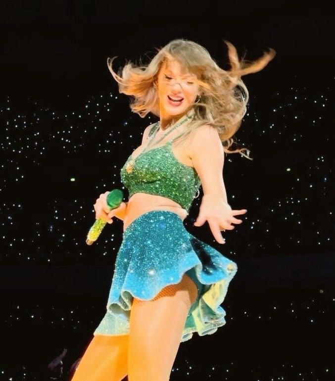 Taylor Swift wearing a green top and a blue skirt