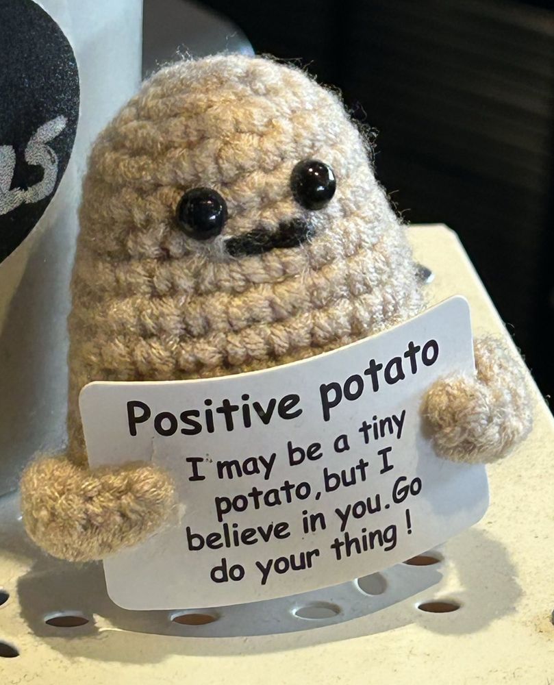 Crochet potato holding an encouraging sign. 