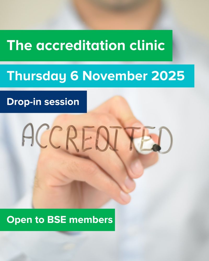 A man writes 'accredited' on a window in board marker, with banners giving the details of the event