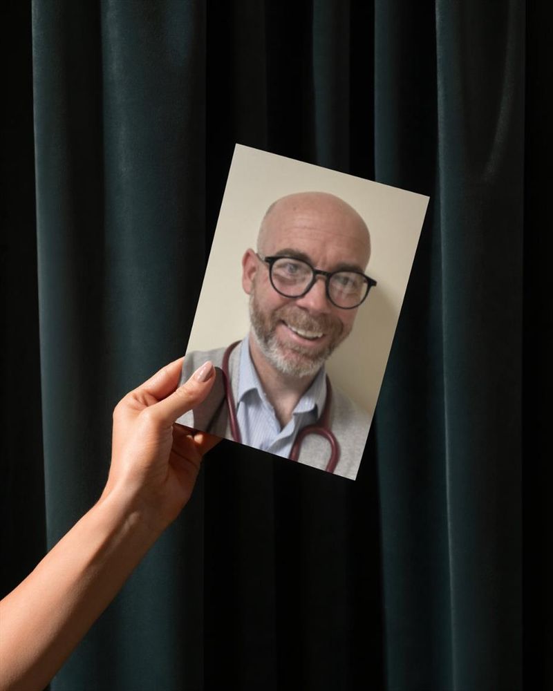 A picture of a hand holding a photo of Martin against a green curtain