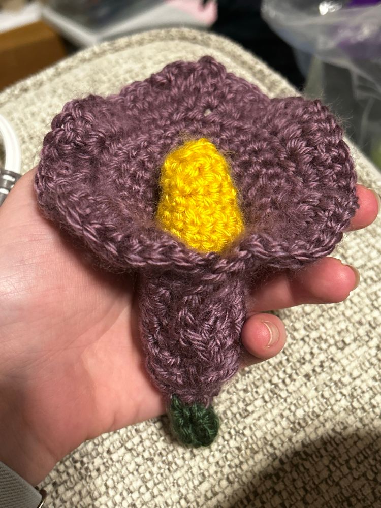 Picture is a crocheted open calla lily in purple with a yellow pollen center and green base