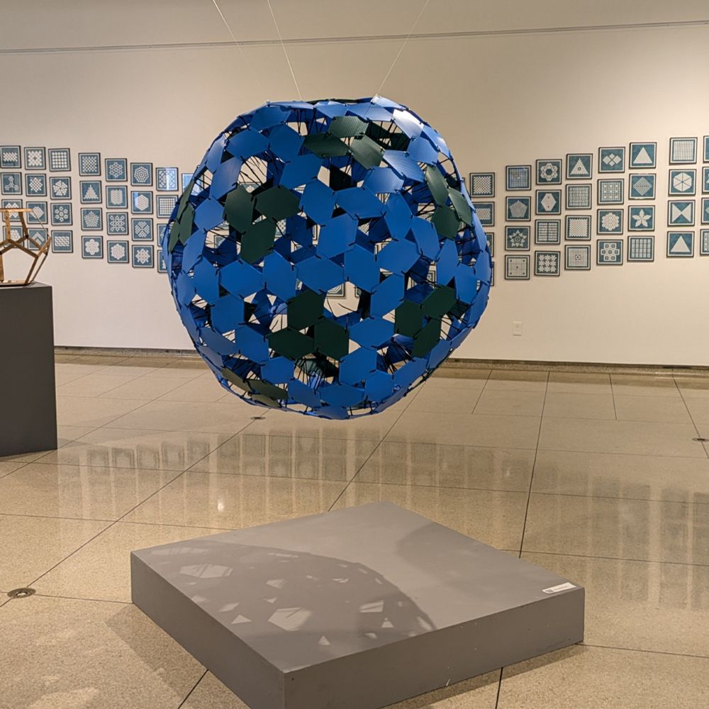 The title is from the same phrase popularized in the 1960s by R. Buckminster "Bucky" Fuller. Fuller also popularized the geodesic dome, which has a related construction. This work is based on the 2,1-Goldberg polyhedron where the edges have been replaced with rhombic pieces of colored corrugated plastic.  This piece is an abstract model of the Earth make from 210 pieces: 60 green pieces and 150 blue pieces. About 71% of the pieces are blue, which is about the same percentage of the Earth's surface covered by water. We are individuals, yet travel through space together, inhabitants on and caretakers of the same tiny planet we call Earth. 
