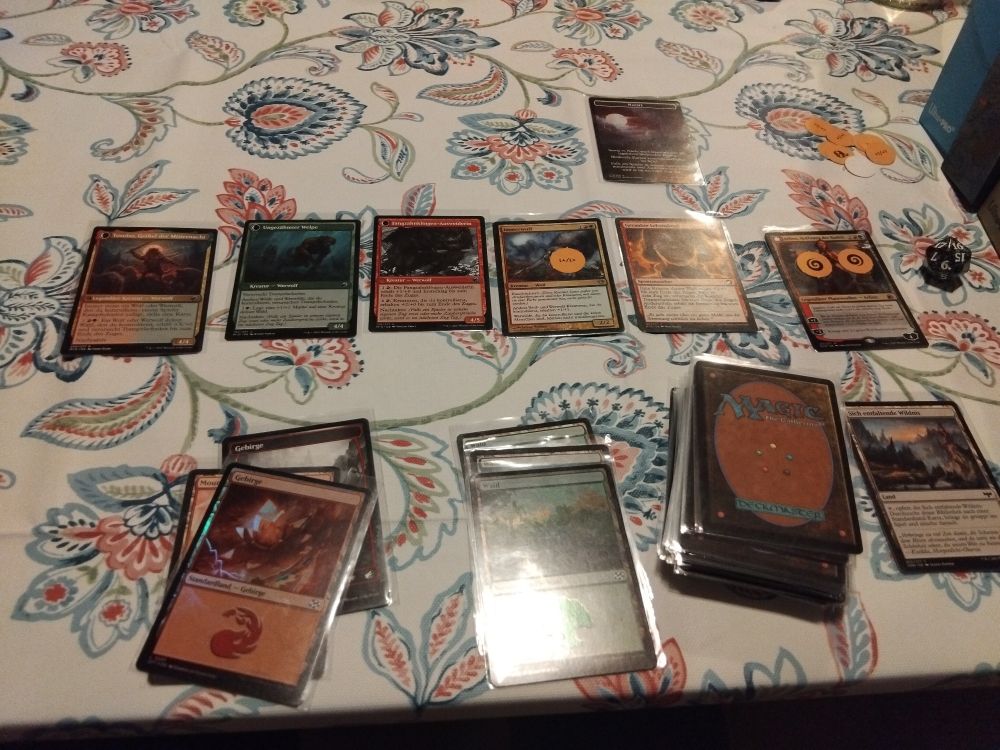 Ein Werwolfdeck aus Magic the Gathering auf einer geblühmten Tischdecke