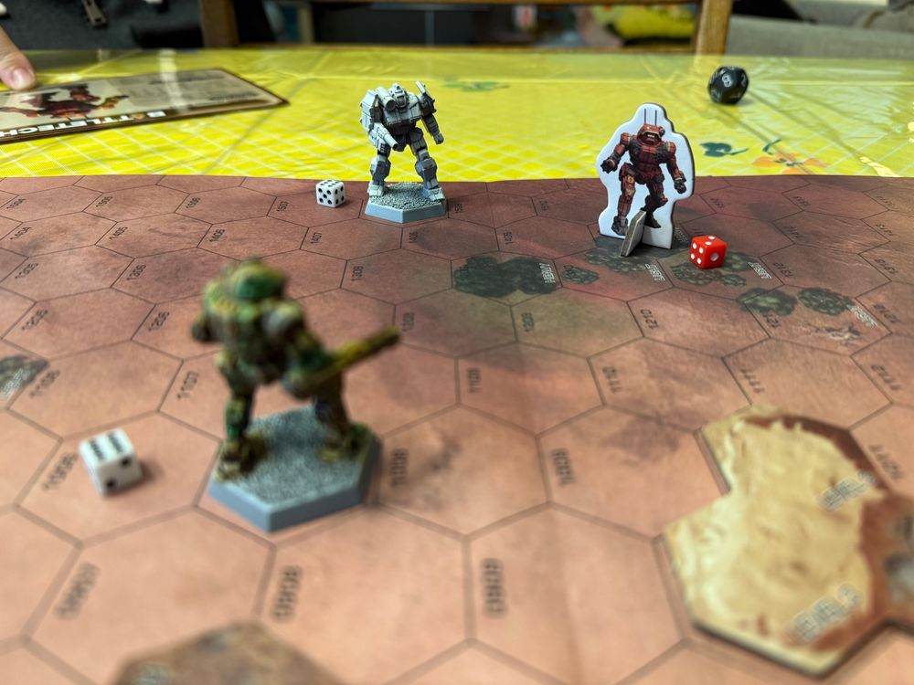 Photo of the mech minis on a hex grid with small d6s next to them marking movement.