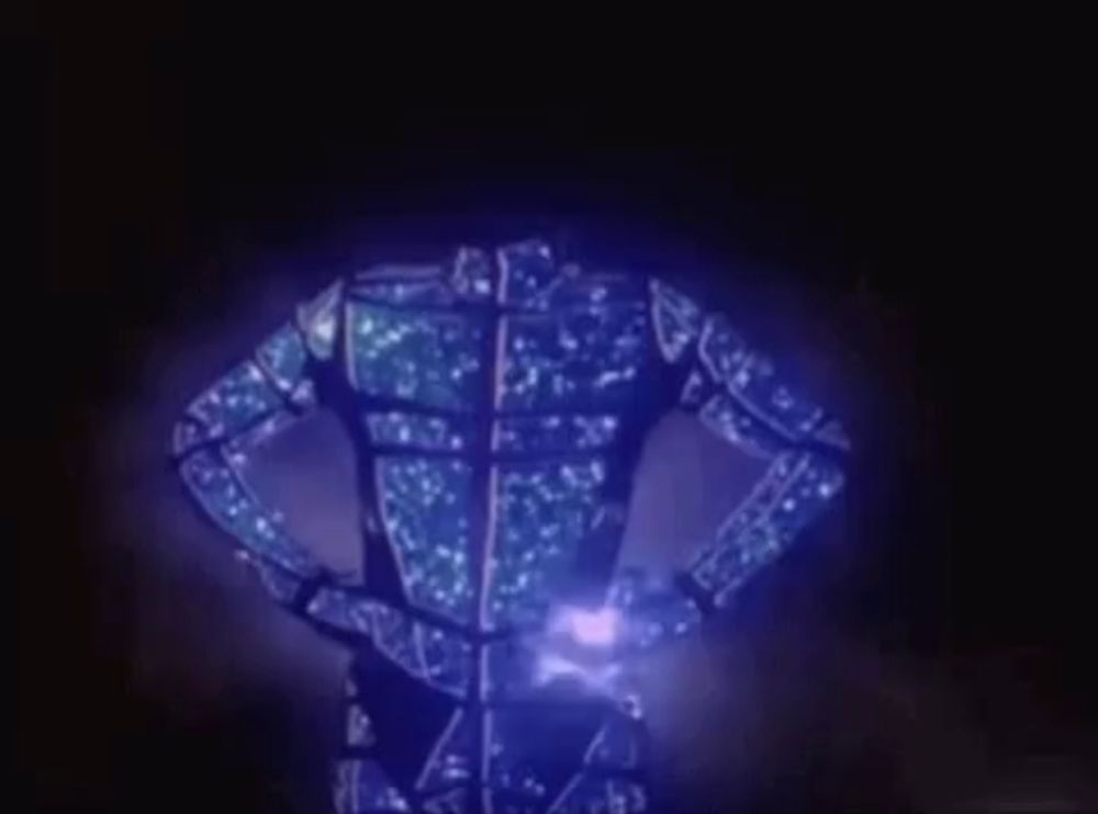 a robot is glowing in the dark with a blue light coming out of it 's chest .