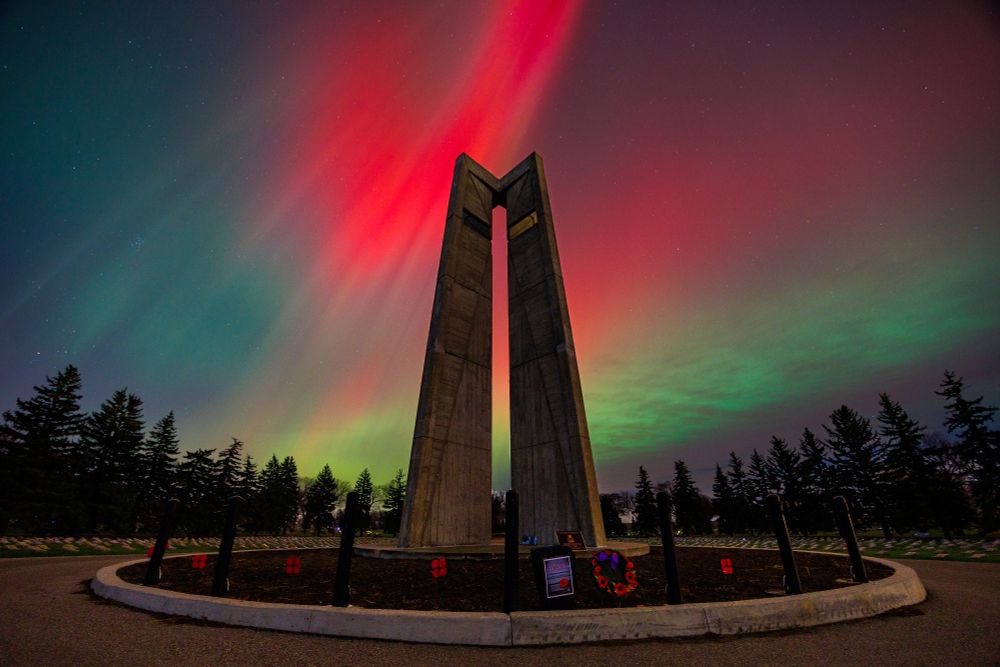 Red and green aurora borealis light up the night sky behind the Veteran's Cenotaph in Regina on Remembrance Day, 2025.  