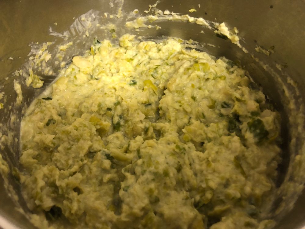 In einem großen Edelstahltopf befindet sich gekochter, anpürierter und mit Sahne und Muskat vermengter Rosenkohl.