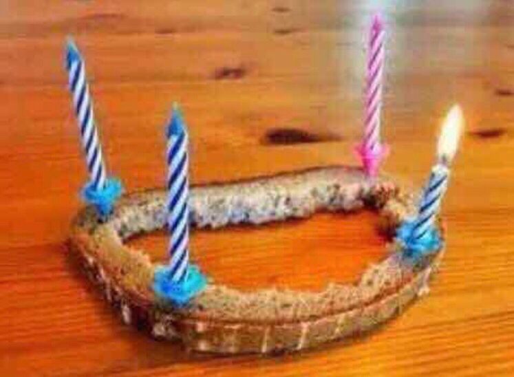 Auf dem Rand einer ausgehölten Brotscheibe stehen vier kleine Kerzen, von denen zwei angezündet sind.