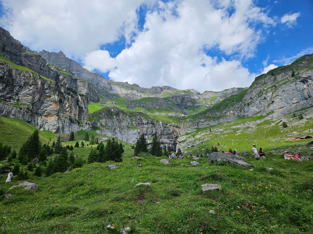 Looking up towards the ridge of alpine mountains with white clouds in the blue sky (Oeschinensee)