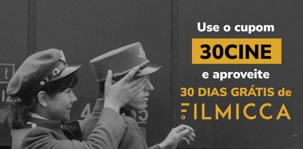 Imagem do filme Trens Estreitamente Vigiados, onde uma personagem coloca as mãos no rosto do outro personagem, para fazer uma surpresa. Na imagem está escrito Use o cupom 30CINE e aproveite 30 dias grátis de FILMICCA. Filmicca é um streaming brasileiro de cinema mundial, do clássico ao contemporâneo.