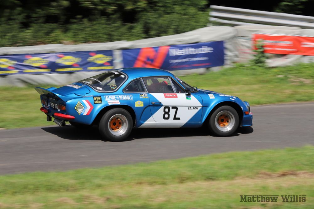 Metallic blue Alpine-Renault A110 at speed, panning shot from the right