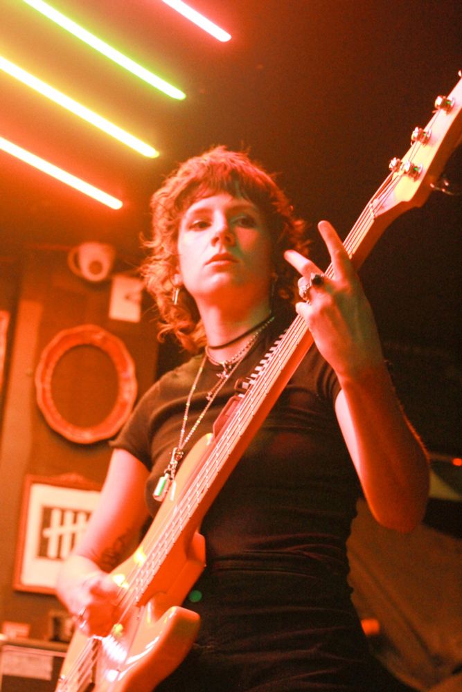 a photo of a person playing guitar illuminated by warm tones. oranges, reds, and yellows. there's some green as well