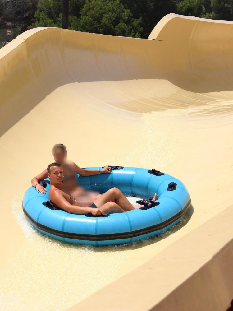 Me and another person (blurred) in a blue inflatable raft going down a big slide in Mallorca July 2025