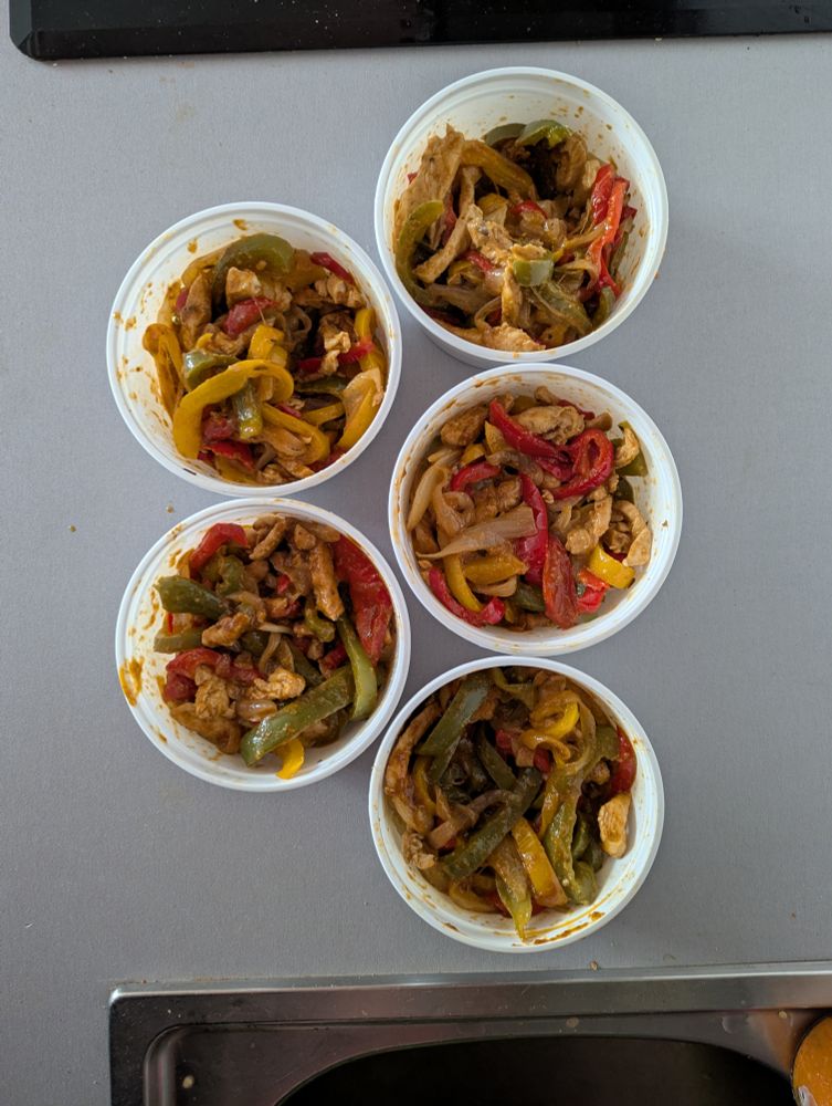 Cinco recipientes de plástico blanco, de los de comida a domicilio, repletos de farsa para fajitas. 