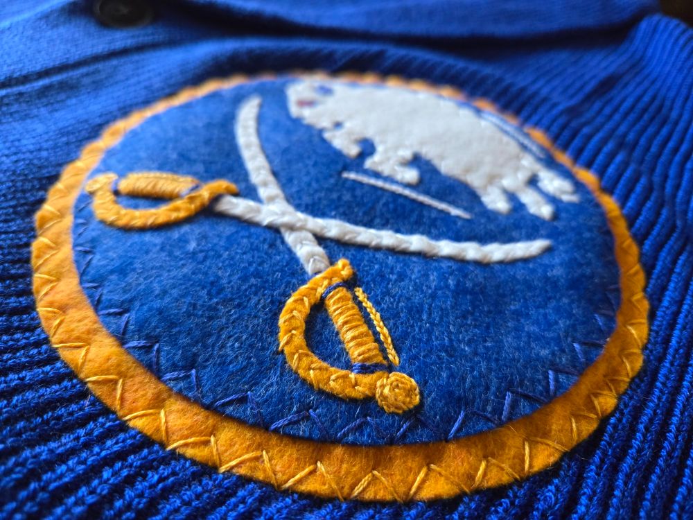 Close up of embroidered sabres logo, sword handle nearest