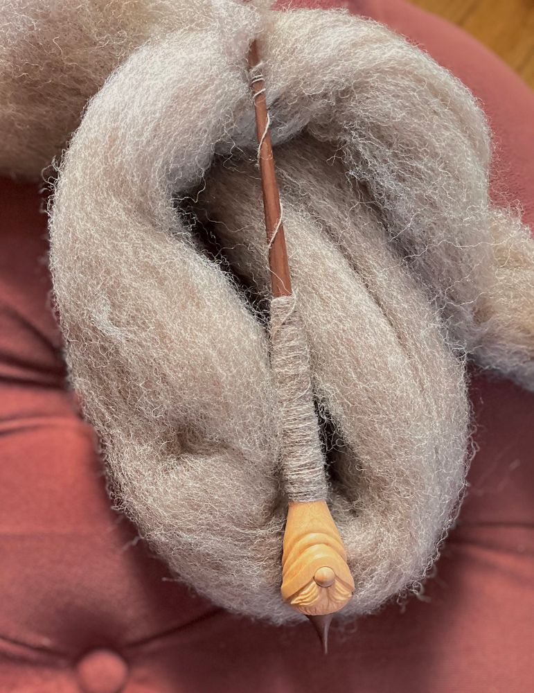 Woodland Handcraft gnome spindle laying in a pile of grey/beige carded wool.