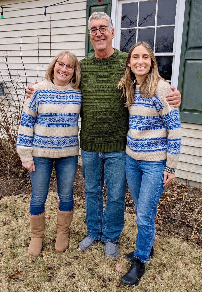 Three people posing outside on a winter day wearing hand-knit sweaters. On the left and right the two people are wearing matching #porcelainsweaters made with Porcelain Sweater Solo pattern by Lene Holme Samoe in a cream and blue color. Center is a taller person wearing a dark green sweater knit using Sweater No.18 pattern by My Favorite Things.