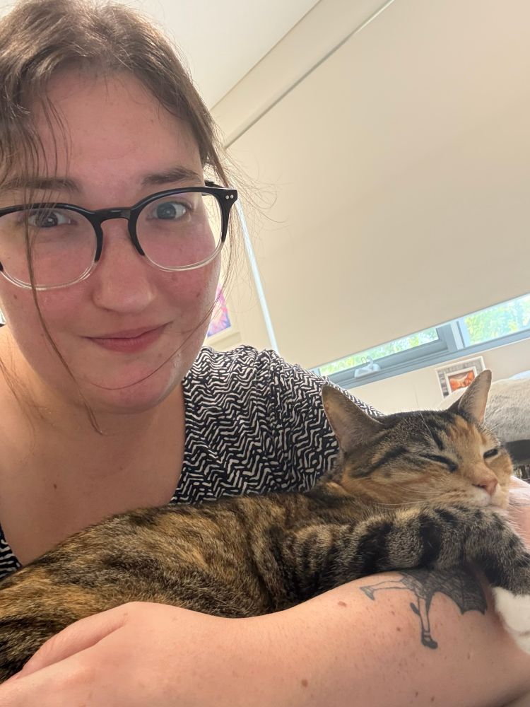 a selfie of nicky the friendly shark with a cat curled up in their arms
