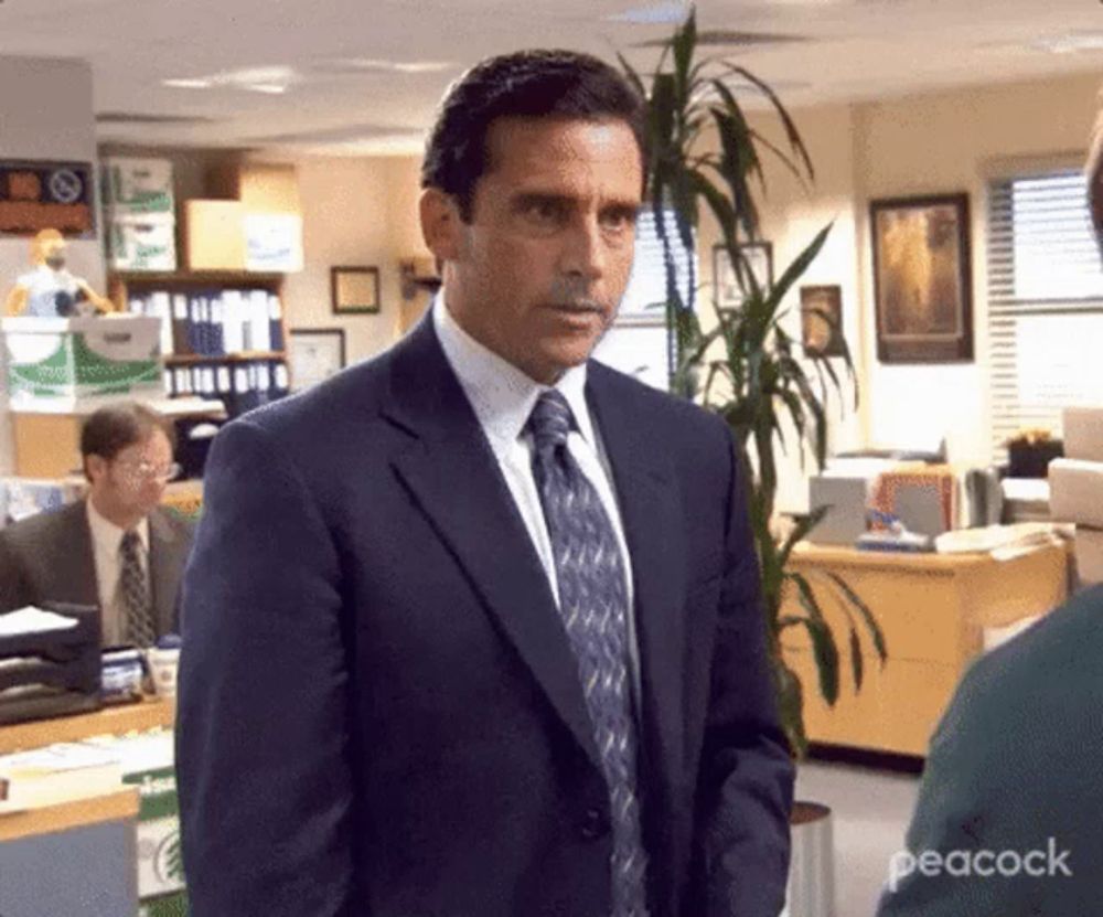 a man in a suit and tie is standing in an office with a plant in the background .