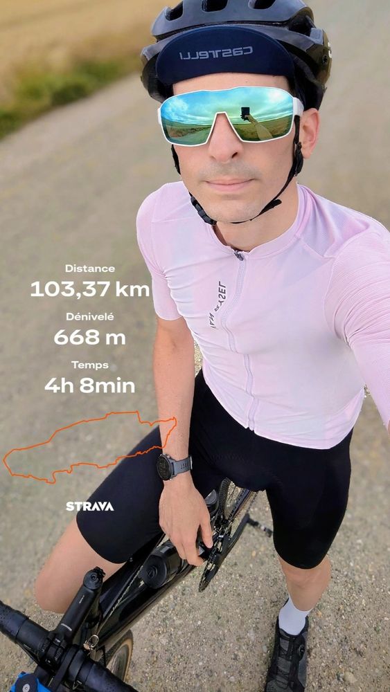 Moi sur mon vélo en maillot rose clair cuissard noir chaussures noires chaussettes blanche vélo noir, lunettes blanche casque noir. Selfie pris en contre-plongée. La route en arrière-plan. Écrit à gauche : 103.37 km, 668 dénivelé,  4h8