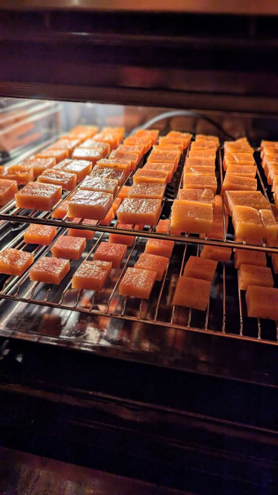 Carrés de pâte de coing orange qui sèchent sur des grilles dans un four