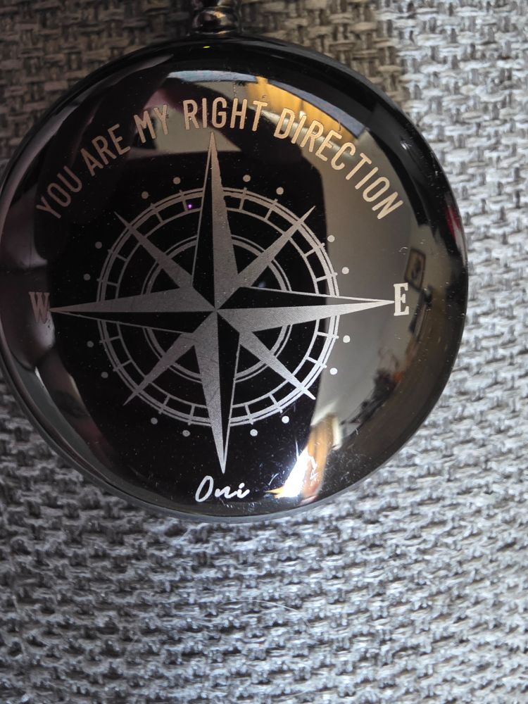 Black shiny pocket watch exterior with compass pattern, "You are my right direction" above symbol, "Oni" below.
