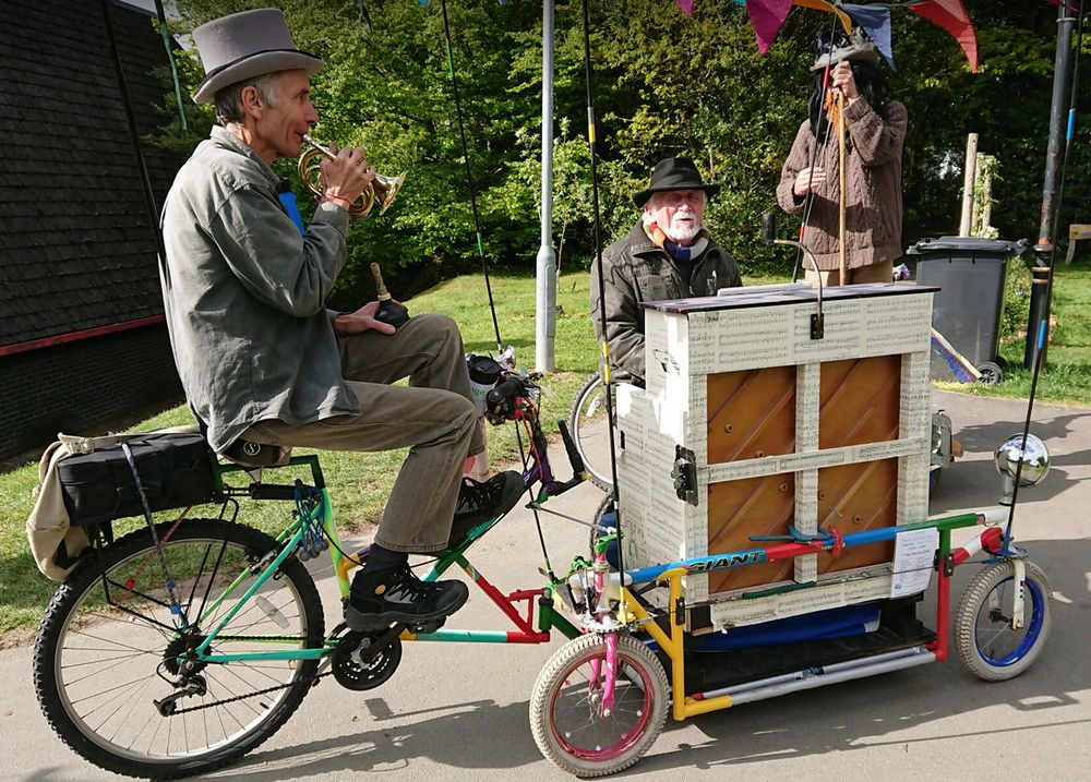 Modified bicycle with 3 wheel front half with platform supporting small piano and piano player