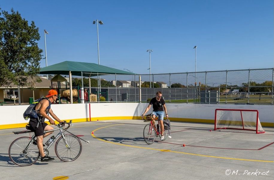 Two cyclists playing polo